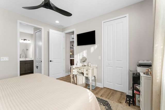 bedroom with light hardwood / wood-style floors, ceiling fan, and ensuite bath