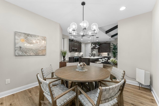 dining space featuring lofted ceiling, a chandelier, and light hardwood / wood-style flooring