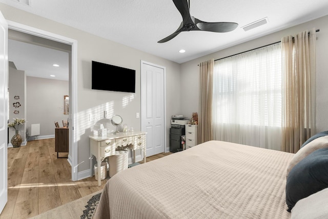 bedroom with ceiling fan, light hardwood / wood-style floors, and a closet