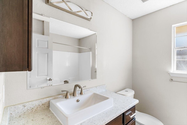 bathroom featuring vanity, toilet, and a shower