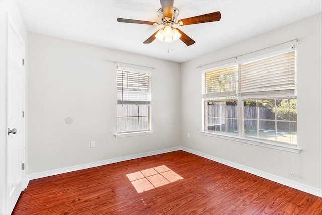 empty room with wood-type flooring, a healthy amount of sunlight, and ceiling fan