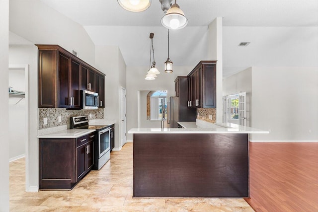 kitchen featuring pendant lighting, appliances with stainless steel finishes, dark brown cabinets, tasteful backsplash, and kitchen peninsula