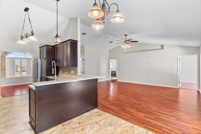 kitchen featuring lofted ceiling, tasteful backsplash, hanging light fixtures, kitchen peninsula, and ceiling fan