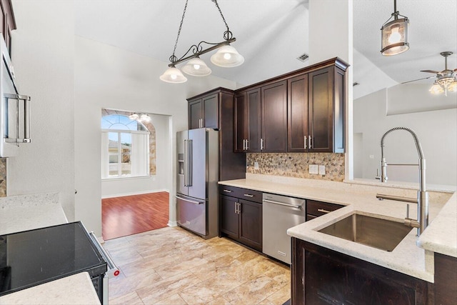 kitchen with vaulted ceiling, decorative backsplash, hanging light fixtures, stainless steel appliances, and dark brown cabinets