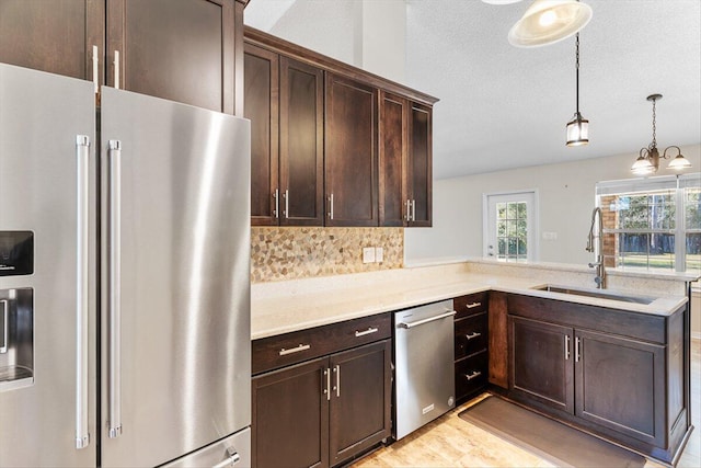 kitchen featuring appliances with stainless steel finishes, pendant lighting, sink, kitchen peninsula, and dark brown cabinets