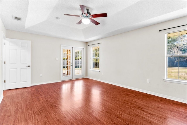 unfurnished room with french doors, wood-type flooring, a textured ceiling, a tray ceiling, and ceiling fan