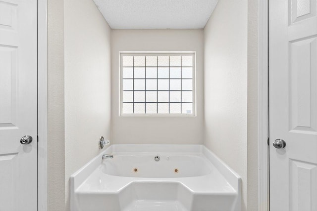 bathroom featuring plenty of natural light, a tub, and a textured ceiling