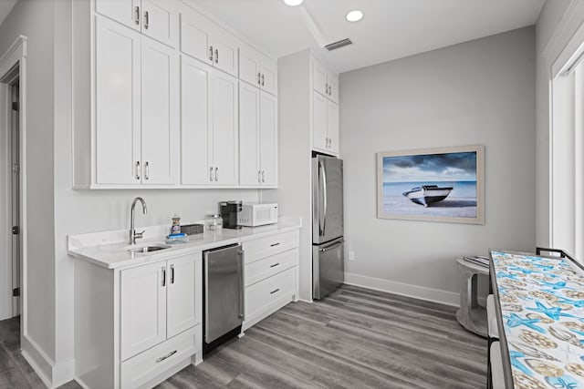 kitchen with white cabinetry, sink, hardwood / wood-style floors, and appliances with stainless steel finishes