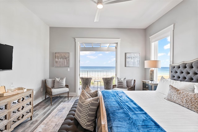 bedroom with hardwood / wood-style flooring, ceiling fan, and a water view