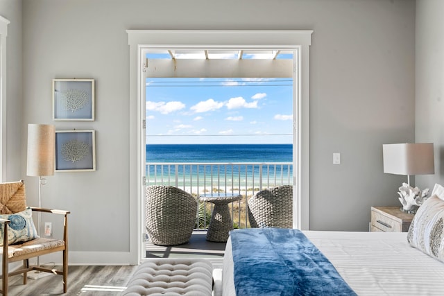 bedroom with multiple windows, hardwood / wood-style floors, and a water view