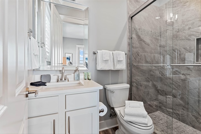 bathroom featuring vanity, a shower with door, and toilet