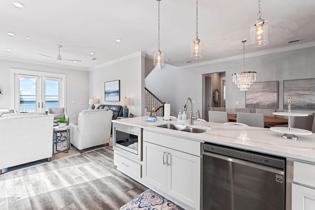 kitchen featuring sink, pendant lighting, stainless steel appliances, light stone countertops, and white cabinets