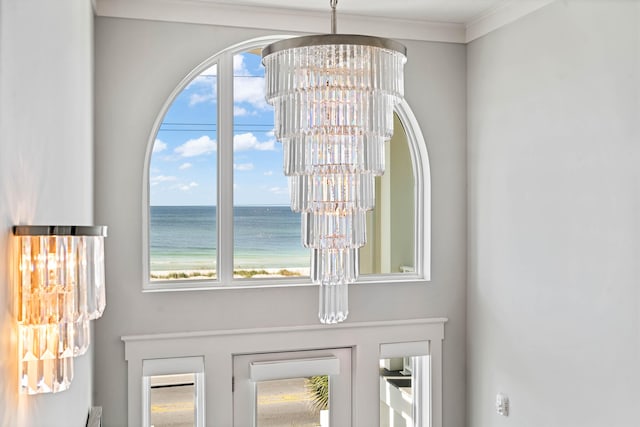 interior details with ornamental molding, a water view, an inviting chandelier, and french doors