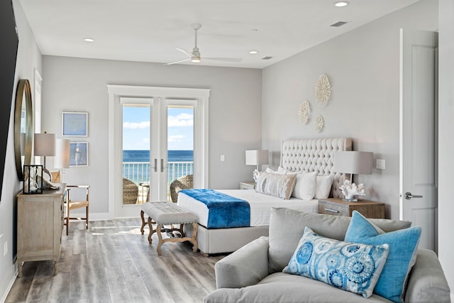 bedroom with ceiling fan, access to exterior, a water view, french doors, and light wood-type flooring