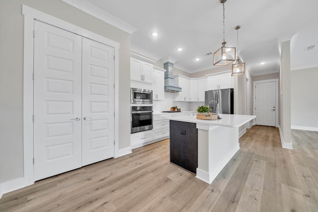 kitchen featuring hanging light fixtures, custom range hood, stainless steel appliances, a kitchen island with sink, and white cabinets