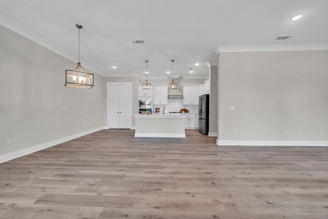 unfurnished living room featuring an inviting chandelier, ornamental molding, and light hardwood / wood-style flooring