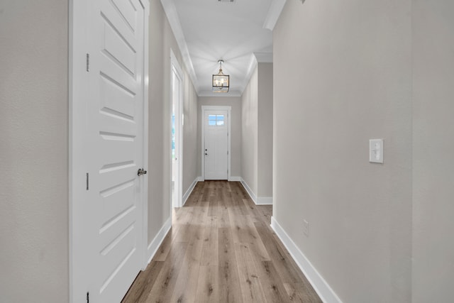 doorway with crown molding, an inviting chandelier, and light hardwood / wood-style floors