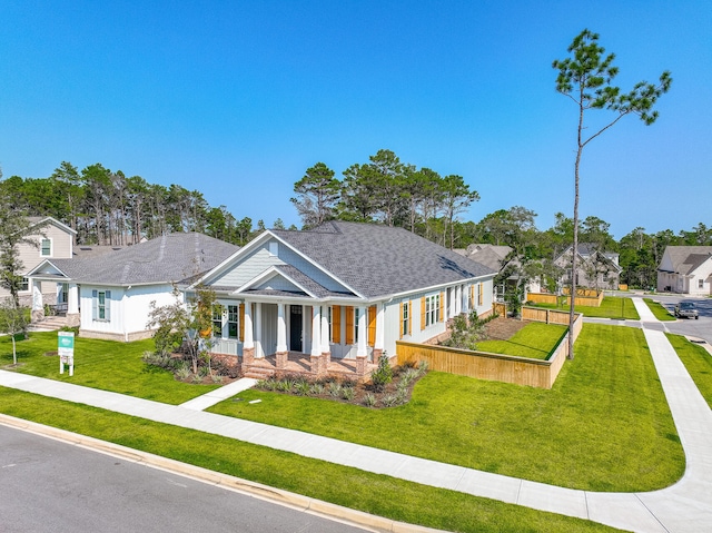 view of front of property with a porch, a front yard, fence, and a shingled roof