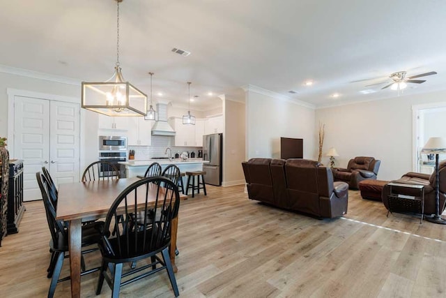 dining space featuring light wood-style flooring, visible vents, and crown molding