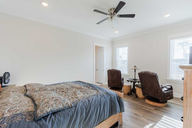 bedroom with multiple windows, crown molding, wood-type flooring, and ceiling fan