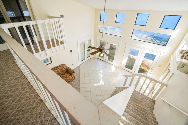 stairway with ceiling fan and a high ceiling