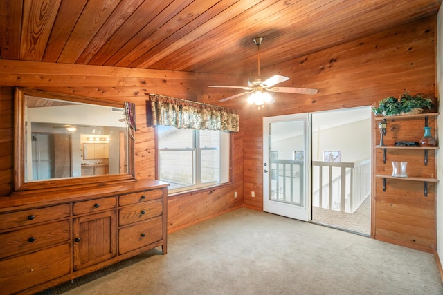 interior space with ceiling fan, light colored carpet, wooden ceiling, and wooden walls