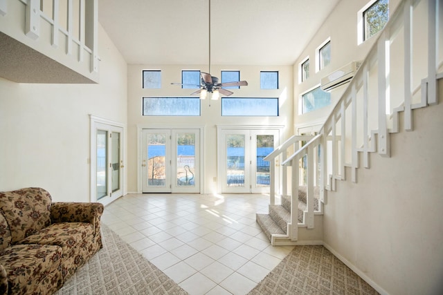 tiled foyer with ceiling fan, a towering ceiling, and a wall unit AC