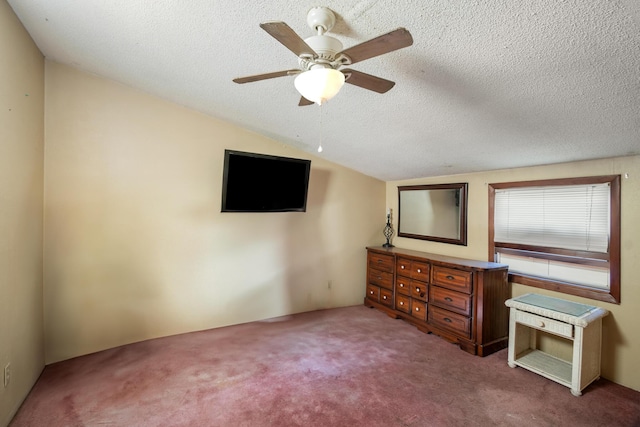 unfurnished bedroom featuring a textured ceiling, vaulted ceiling, ceiling fan, and carpet flooring