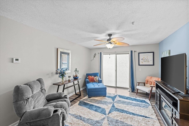 living room featuring hardwood / wood-style flooring, ceiling fan, and a textured ceiling