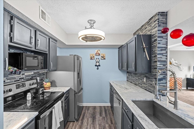 kitchen with appliances with stainless steel finishes, sink, dark hardwood / wood-style flooring, and decorative backsplash