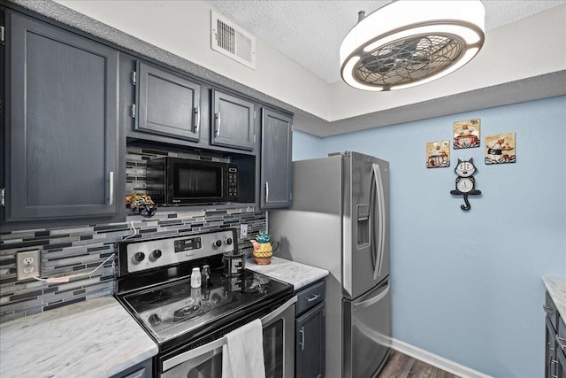 kitchen featuring appliances with stainless steel finishes, dark hardwood / wood-style floors, tasteful backsplash, gray cabinetry, and a textured ceiling