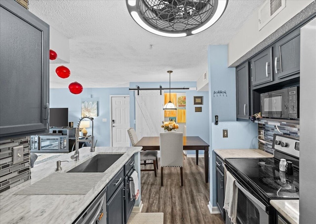 kitchen with sink, stainless steel electric range, black microwave, pendant lighting, and a barn door