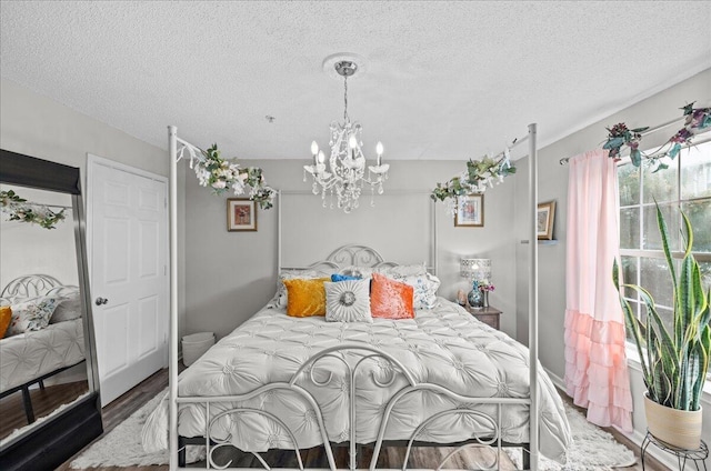 bedroom with dark hardwood / wood-style flooring, a textured ceiling, and a notable chandelier