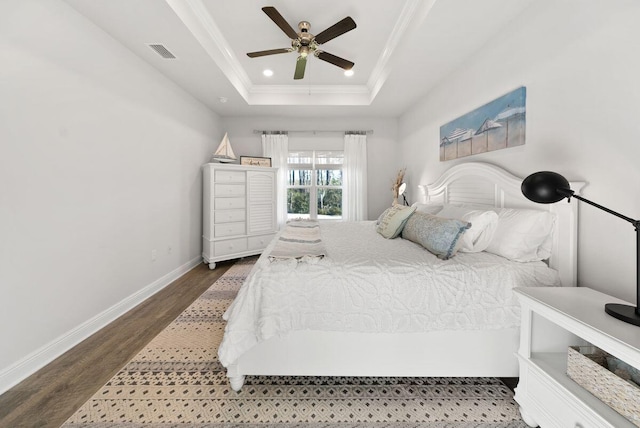 bedroom with wood-type flooring, ornamental molding, ceiling fan, and a tray ceiling