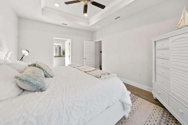 bedroom with hardwood / wood-style flooring, ornamental molding, ceiling fan, a raised ceiling, and ensuite bath