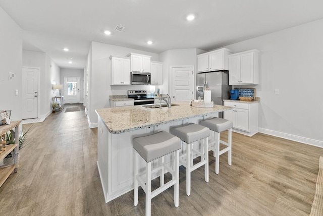 kitchen featuring stainless steel appliances, white cabinetry, sink, and a center island with sink