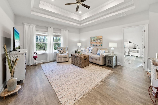 living room featuring hardwood / wood-style floors, crown molding, a raised ceiling, and ceiling fan