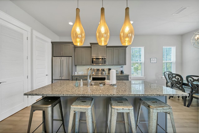 kitchen with pendant lighting, light stone counters, and stainless steel appliances