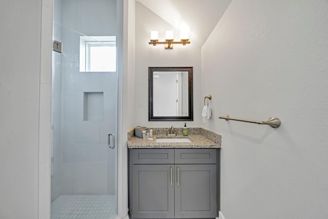 bathroom with lofted ceiling, vanity, and a shower with door