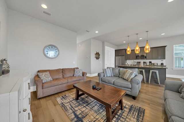 living room featuring sink and light hardwood / wood-style flooring