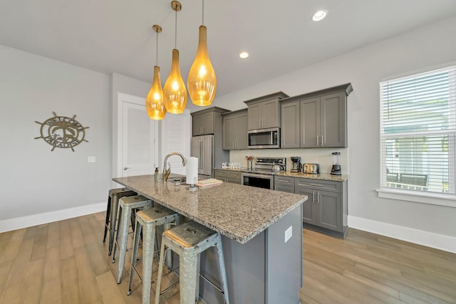 kitchen featuring pendant lighting, sink, a breakfast bar, stainless steel appliances, and light stone counters