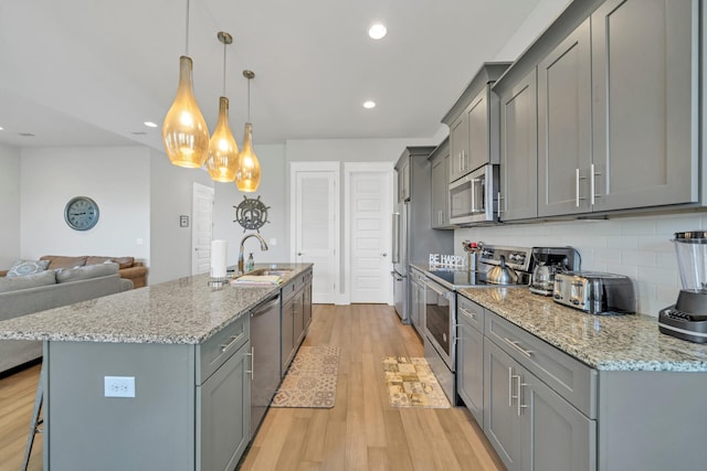 kitchen featuring stainless steel appliances, gray cabinets, pendant lighting, and backsplash