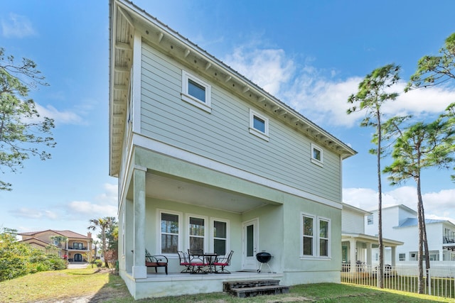 rear view of property with a patio and a lawn