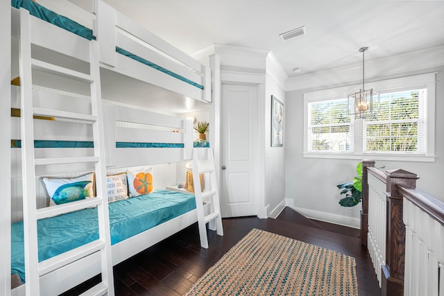 bedroom with a notable chandelier and dark wood-type flooring