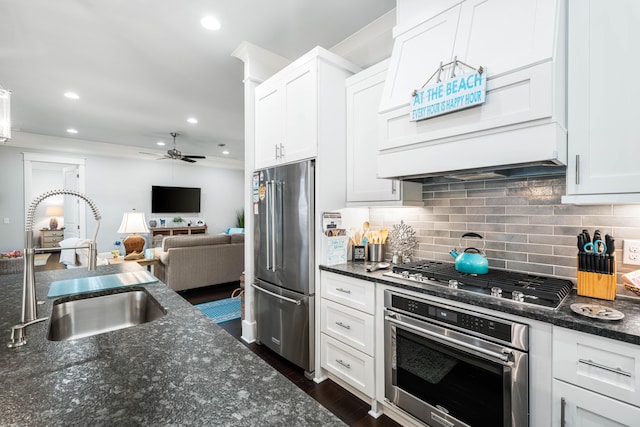 kitchen featuring appliances with stainless steel finishes, sink, dark stone countertops, and white cabinets