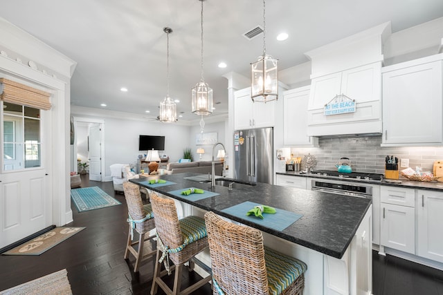 kitchen with a kitchen bar, sink, appliances with stainless steel finishes, an island with sink, and white cabinets