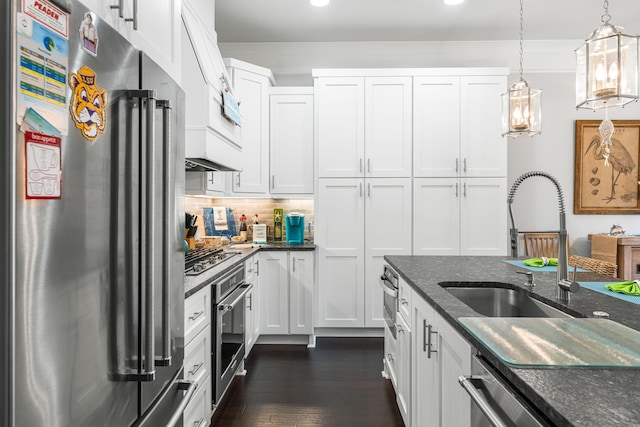 kitchen featuring appliances with stainless steel finishes, dark stone counters, hanging light fixtures, and white cabinets