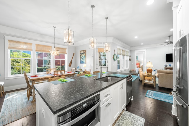 kitchen featuring white cabinetry, stainless steel appliances, a kitchen island with sink, and pendant lighting