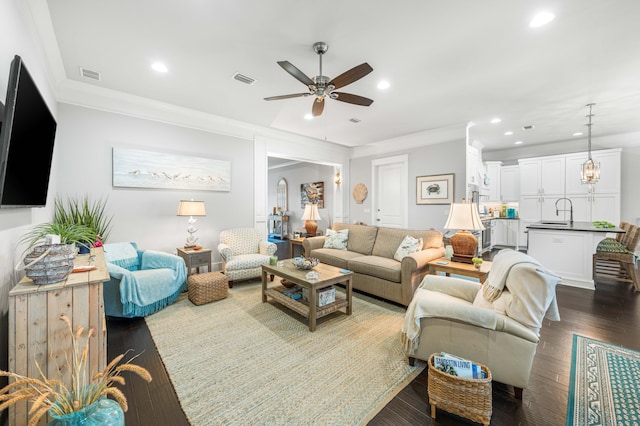 living room featuring sink, dark wood-type flooring, ornamental molding, and ceiling fan