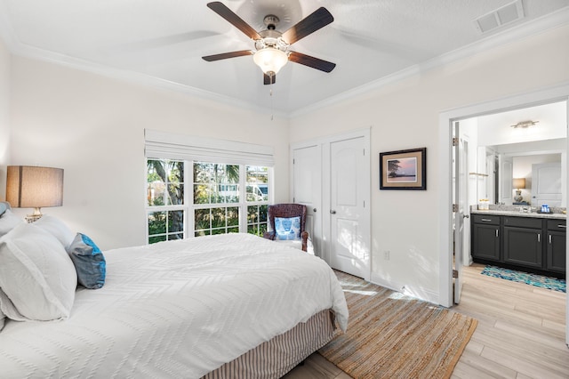 bedroom featuring ceiling fan, ensuite bath, ornamental molding, and light wood-type flooring